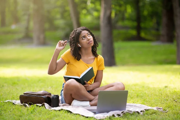 远距离教育。有远见的非洲裔美国女孩在公园拿着笔记本电脑和笔记本做家务 — 图库照片