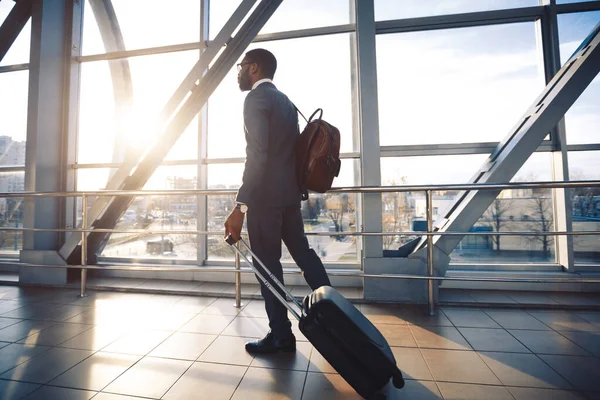 Schwarzer Unternehmer Mann läuft mit Reisekoffer im Flughafen drinnen — Stockfoto