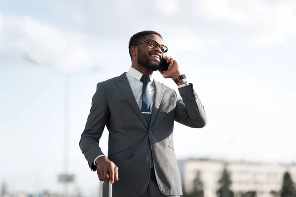 Επιχειρηματίας Μιλώντας στο κινητό τηλέφωνο στέκεται με ταξιδιωτική βαλίτσα — Φωτογραφία Αρχείου