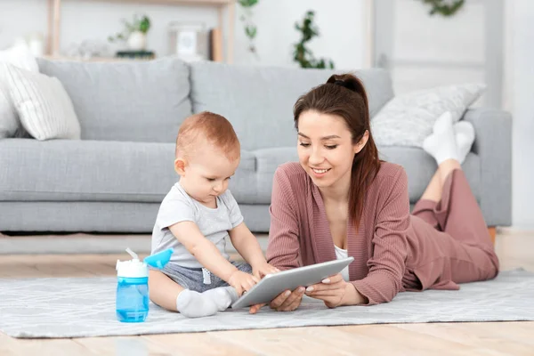 Jeune maman et son bébé fils jouant retarder les jeux sur tablette numérique — Photo