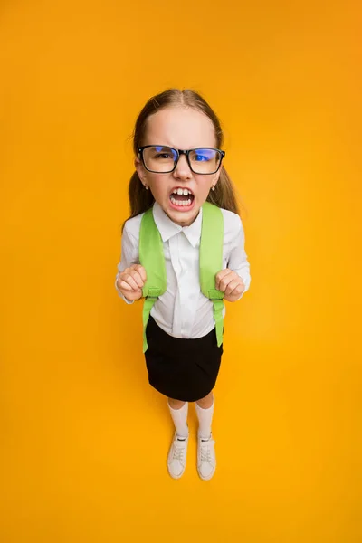 Soddisfatto studentessa in occhiali accigliato in piedi su sfondo giallo Studio — Foto Stock