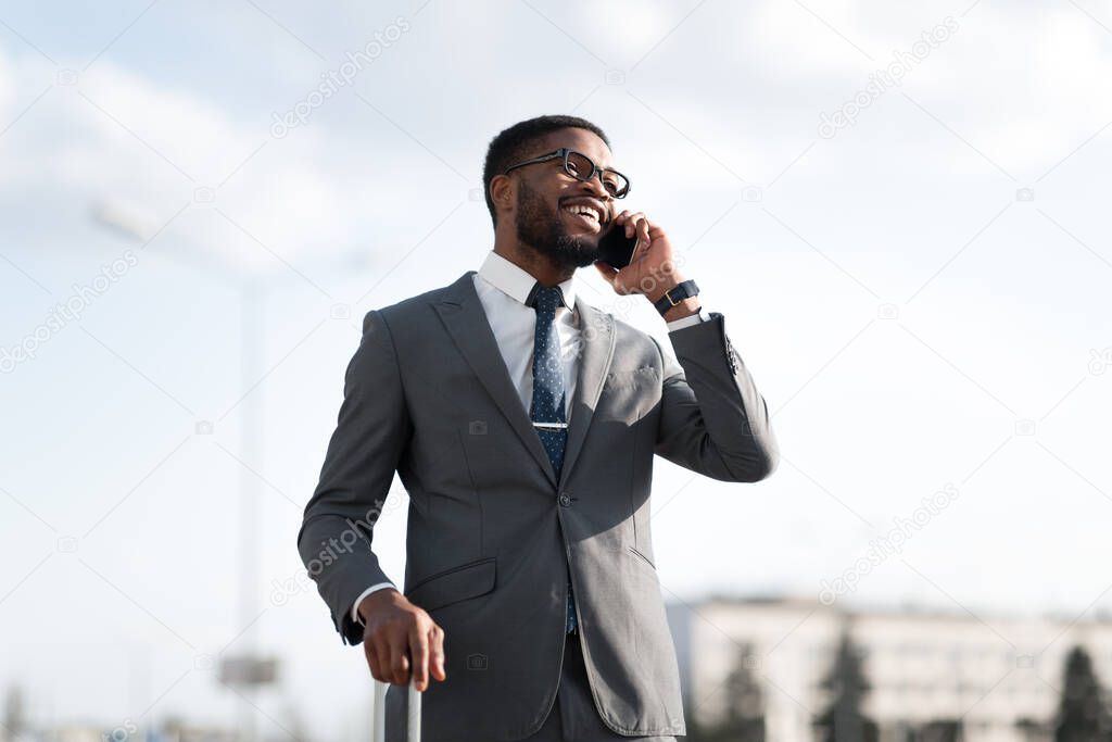 Business Man Talking On Cellphone Standing With Travel Suitcase Outdoors