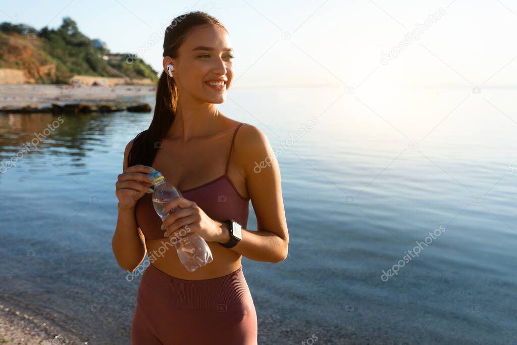 Happy healthy runner standing on beach listening to music