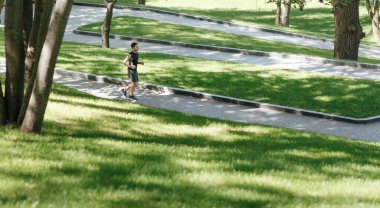 Açık havada fiziksel aktivite. Spor giyimli bir adam pist boyunca koşuyor.