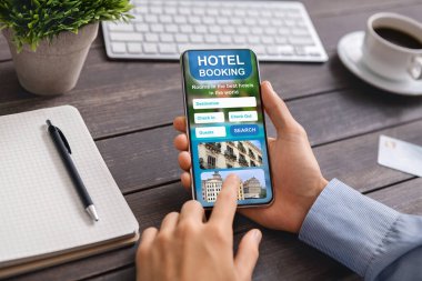 Açık otel rezervasyon uygulaması olan akıllı telefon erkeklerin elinde.
