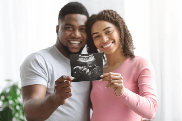 Sorrindo casal grávida mostrando imagem de ultra-som de seu bebê — Fotografia de Stock