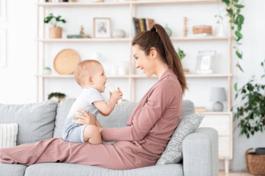 Sevgi dolu bir aile. Anne ve küçük bebeği evde oynuyorlar.