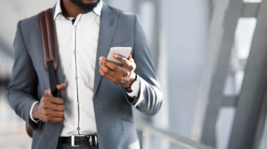 İş gezisindeki adam havaalanında akıllı telefon kullanıyor, kırpılmış.