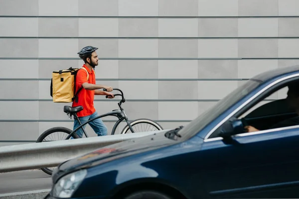 Entrega por correio na cidade. Cara no capacete e com mochila, passando pela cidade com bicicleta — Fotografia de Stock