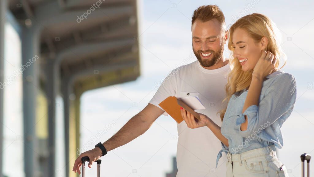 Travel concept. Young couple checking tickets outside