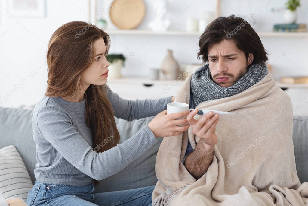 Attentive woman giving her sick boyfriend treatment