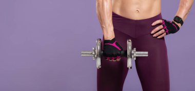 Kas ve güç eğitimine hazır olun. Spor giyimli, kaslı, orta yaşlı bir kadın. Eldivenli ve elinde dambıl tutan akıllı bir saat.