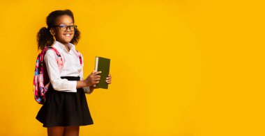 Sarı arkaplan üzerine kitabı olan mutlu siyah liseli kız pozları, Panorama