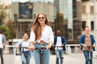 Mutlu gençler elektrikli scooterlara biniyor.