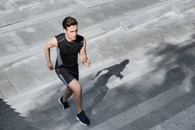 Aktif ve sağlıklı bir yaşam tarzı. Spor kıyafetli adam şehir merdivenlerinden yukarı koşuyor.
