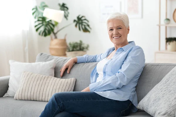 Retrato de mujer mayor relajándose en el sofá en casa, disfrutando del tiempo de jubilación —  Fotos de Stock