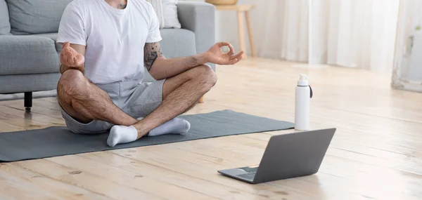 Медитуючий чоловік сидить на підлозі перед ноутбуком — стокове фото