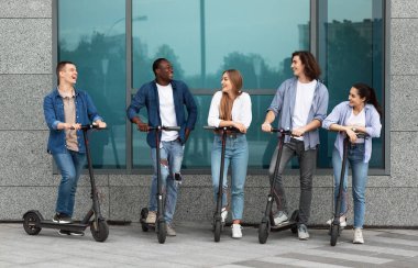 Beş mutlu arkadaş parkta vakit geçirip konuşuyor.