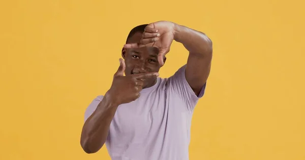 Afro-Amerikaanse man kijkt door vingers grens tot camera — Stockfoto