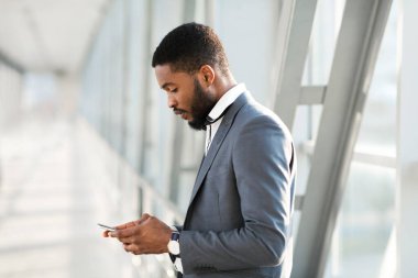 Girişimci, akıllı telefon kullanıyor. Havaalanında uçak bekliyor.
