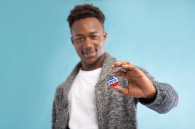 Elinde oy düğmesi olan Afrikalı Amerikalı adam.