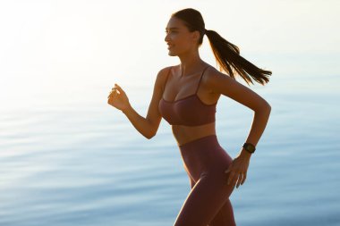 Sabahları kumsalda koşan mutlu kadın.