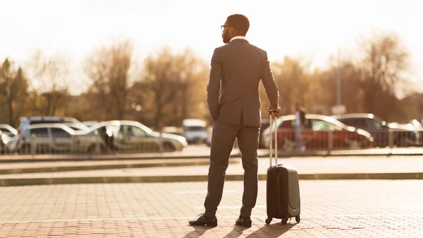 Uomo d'affari in viaggio d'affari in piedi con valigia all'aperto, Panorama, Vista posteriore — Foto Stock