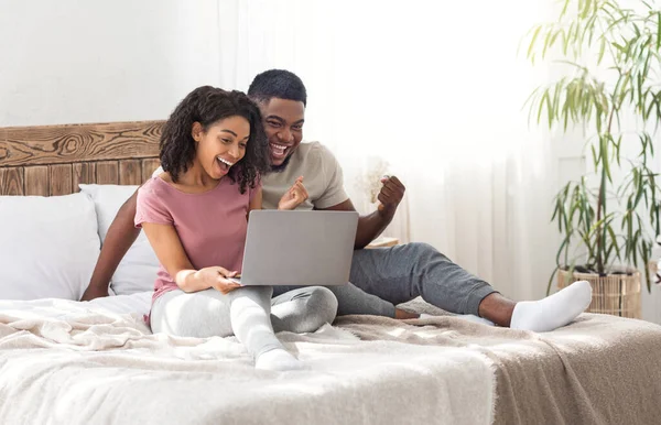 Emocional pareja negra mirando la pantalla del portátil y gritando —  Fotos de Stock
