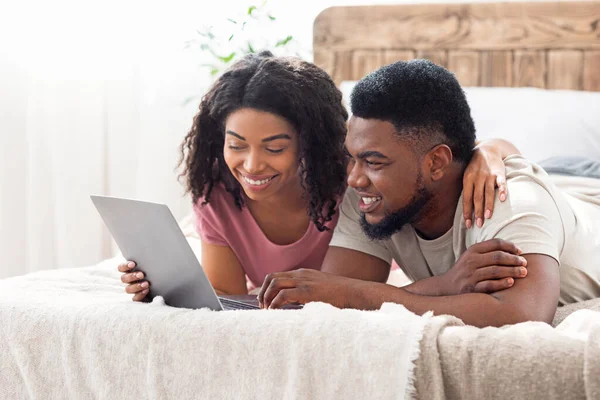 Entspannter afrikanischer Mann und Frau mit Laptop im Schlafzimmer — Stockfoto