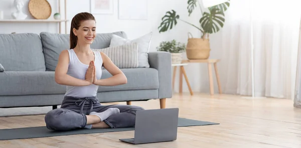 Peaceful young woman meditating at home, using laptop — Stock Photo, Image