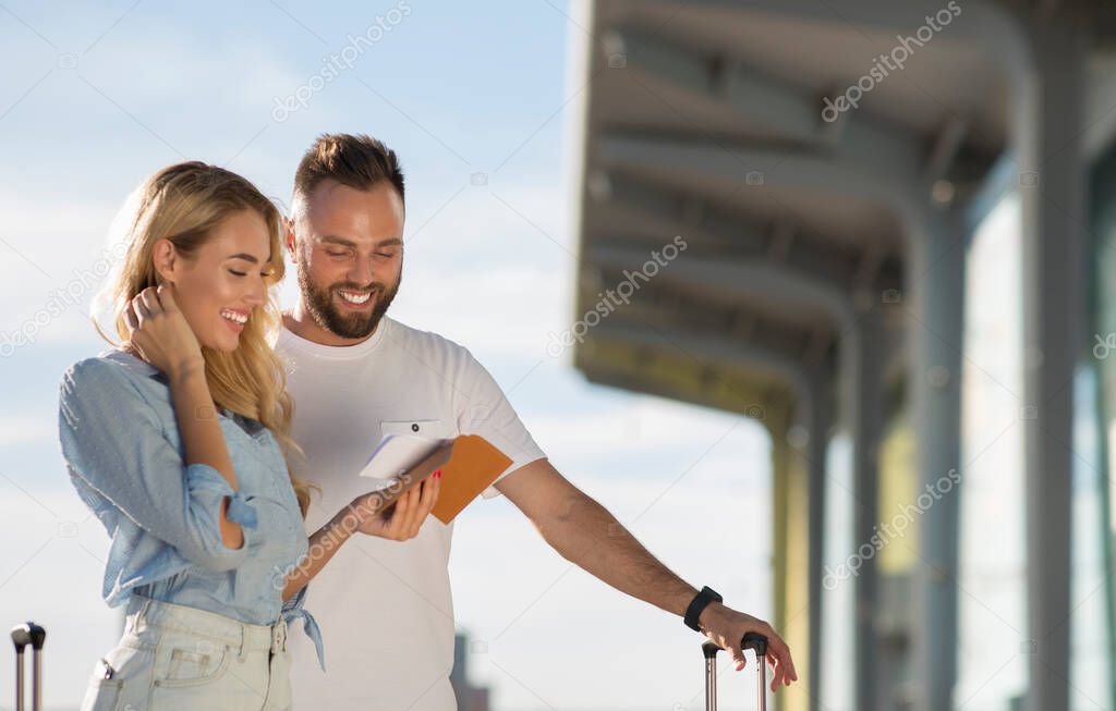 Travel concept. Young couple checking tickets outside