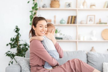 Anne-Çocuk Bağlantısı. Mutlu anne koltuğunda dinlenirken bebeğine sarılıyor.