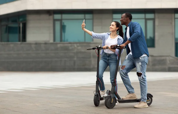 Přátelé s jízdou na motorizovaných koloběžkách, přičemž selfie — Stock fotografie