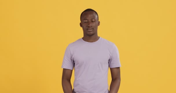 Vreedzame zwarte man bidden, handen klemmen, oranje achtergrond — Stockvideo