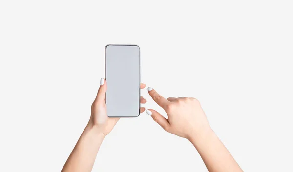 Неузнаваемая молодая девушка показывает смартфон с пустым экраном на белом фоне, макет для дизайна мобильного приложения — стоковое фото