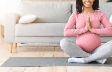 Nilüfer pozisyonunda zenci bir kadının evde yoga yapmasını beklemek.