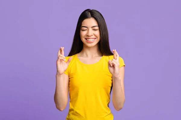Ik maak een wens. glimlachende aziatische vrouw kruisen vingers met gesloten ogen — Stockfoto