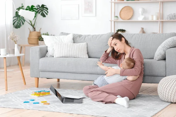 Agotamiento de la maternidad. Mamá cansada amamantando al bebé y trabajando en la computadora portátil en casa —  Fotos de Stock