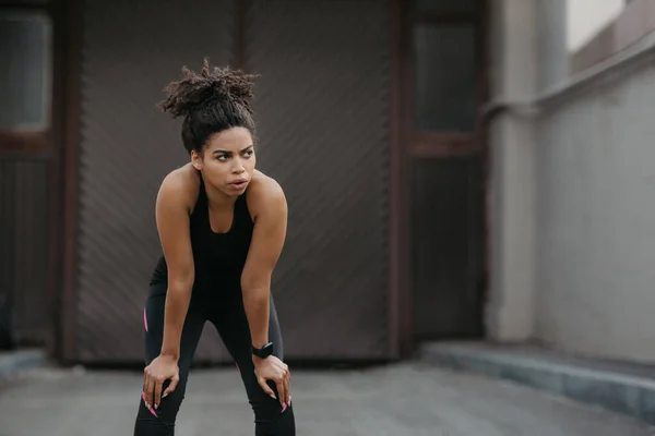 Descanse em treinamento. Cansada menina americana africana com rastreador de fitness respira após correr — Fotografia de Stock