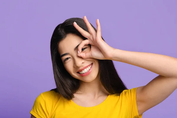 Alegre asiática chica buscando a través de ok signo, cubriendo ojo con ok gesto — Foto de Stock