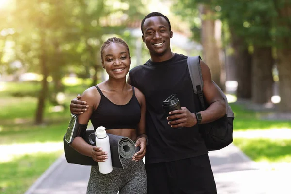 Adatta coppia nera in abbigliamento sportivo in posa insieme dopo l'allenamento all'aperto nel parco — Foto Stock