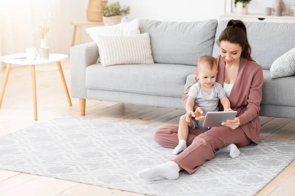 若いお母さんと赤ちゃんは自宅で一緒にデジタルタブレットで遊ぶ — ストック写真
