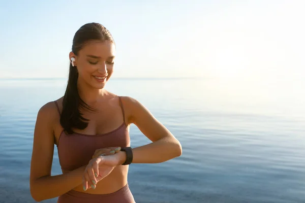 Feliz chica sana corriendo en la playa, usando rastreador — Foto de Stock