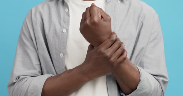 Felismerhetetlen fekete férfi dörzsöli a gyulladt csuklóját, közelről — Stock videók