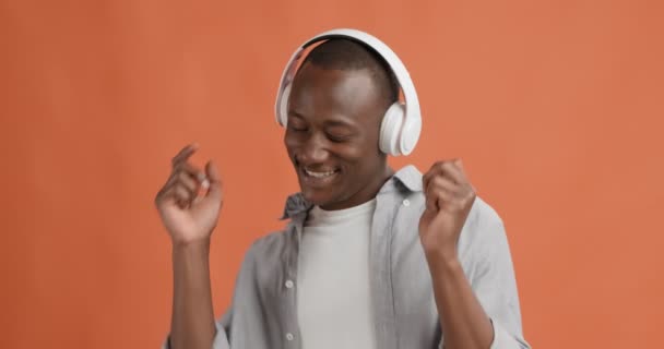 Счастливый черный парень наслаждается музыкой в наушниках, танцует — стоковое видео
