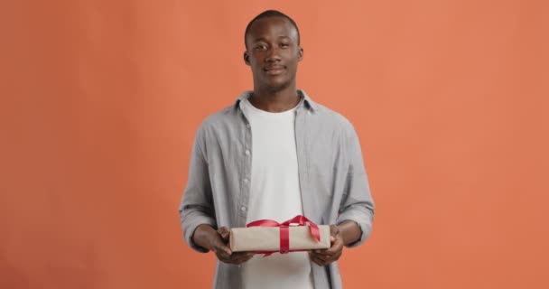 Веселый черный парень предлагает эксклюзивную подарочную коробку для камеры — стоковое видео