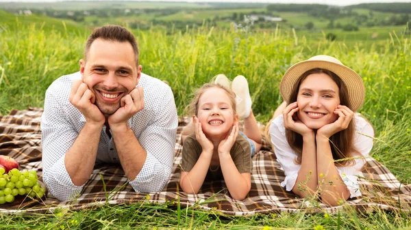 Keluarga muda yang bahagia menghabiskan waktu bersama pada piknik — Stok Foto