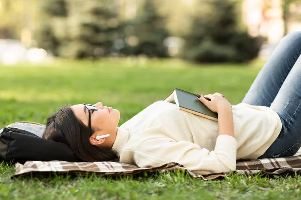 Девочка лежит в летней траве, слушает музыку — стоковое фото