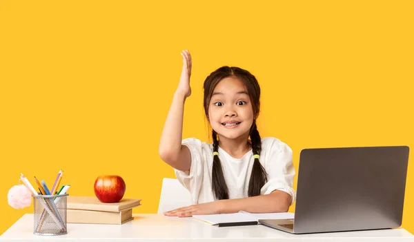 Asiática escolar en portátil levantando mano sobre amarillo estudio fondo —  Fotos de Stock