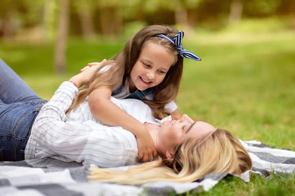 Mor och lilla dotter kramas ligger på rutig i parken — Stockfoto